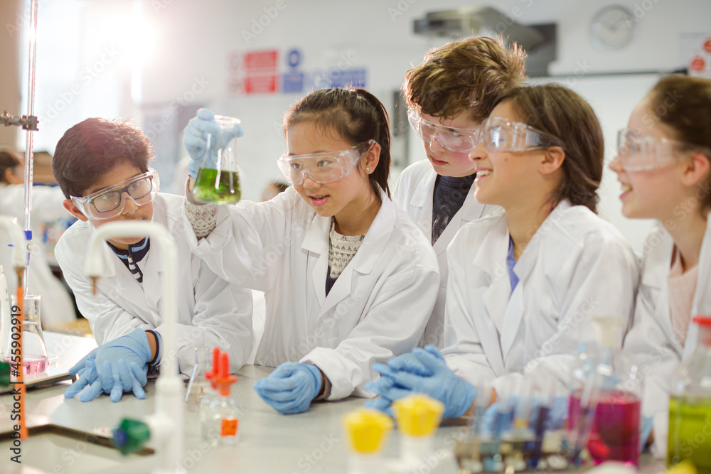 Curious students conducting scientific experiment, examining liquid in beaker in laboratory classroom Curious students conducting scientific experiment, examining liquid in beaker in laboratory classroom