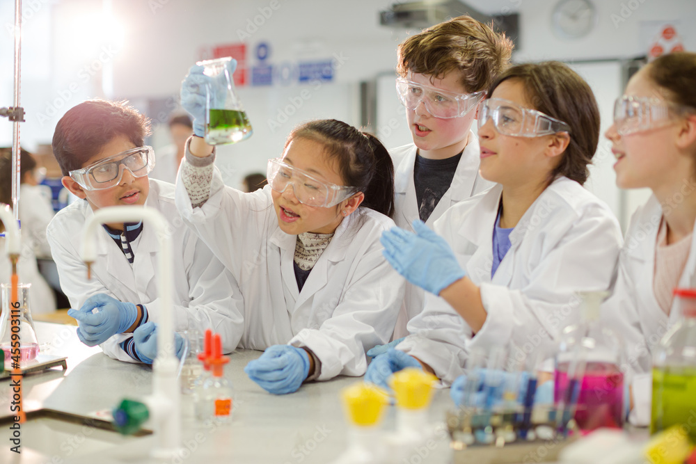 Curious students conducting scientific experiment, examining liquid in beaker in laboratory classroom Curious students conducting scientific experiment, examining liquid in beaker in laboratory classroom