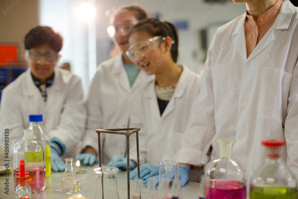 Female teacher and students watching scientific experiment chemical reaction in laboratory classroom Female teacher and students watching scientific experiment chemical reaction in laboratory classroom