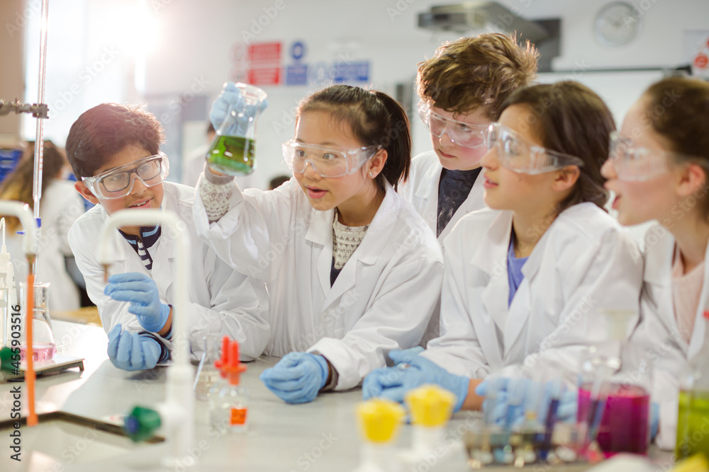 Curious students conducting scientific experiment, examining liquid in beaker in laboratory classroom Curious students conducting scientific experiment, examining liquid in beaker in laboratory classroom