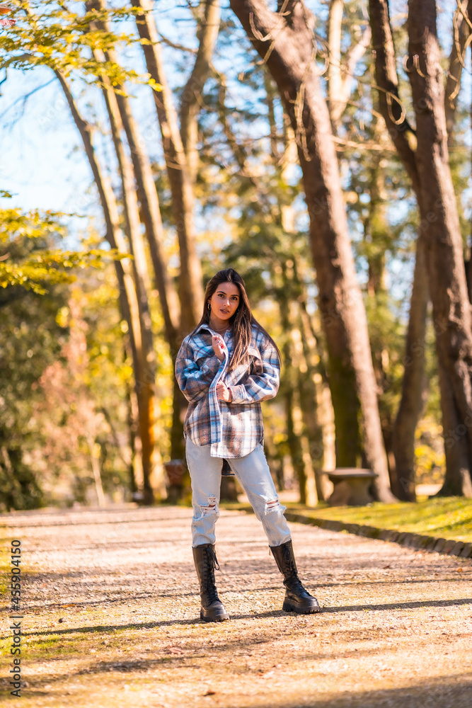Autumn lifestyle, a young Caucasian brunette girl in a plaid wool sweater and ripped jeans in a park Autumn lifestyle, a young Caucasian brunette girl in a plaid wool sweater and ripped jeans in a park