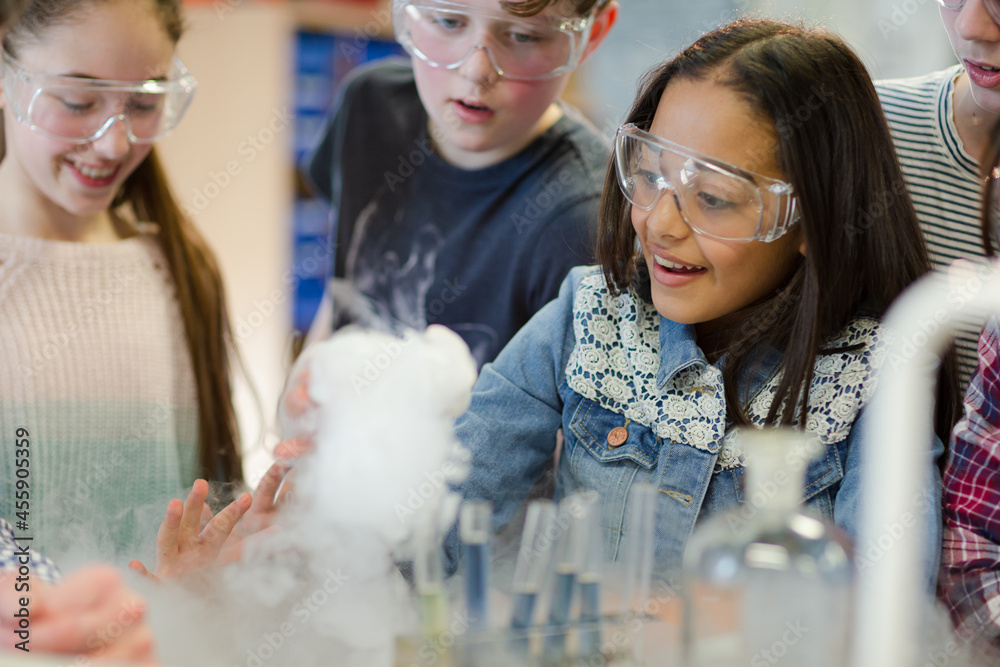 Male teacher and students watching chemical reaction, conducting scientific experiment in laboratory classroom