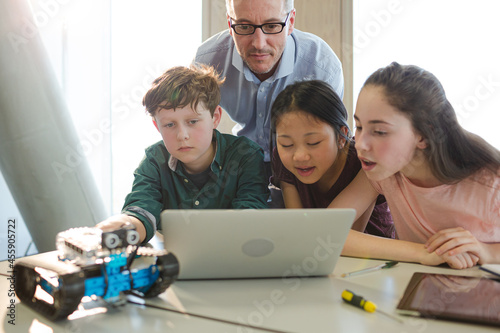 Male teacher and students using laptop in classroom