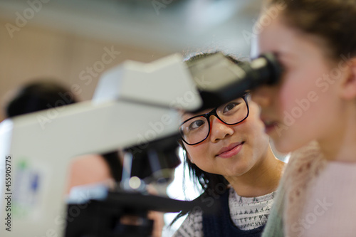 Close up profile girl student using microscope, conducting scientific experiment