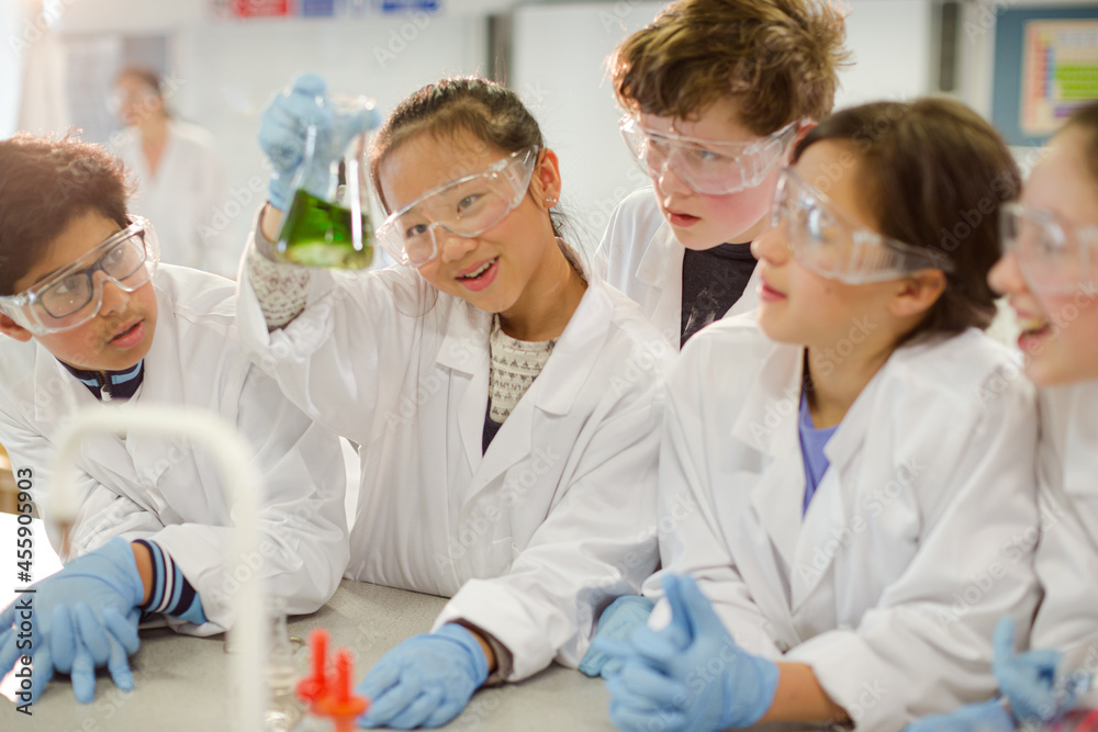 Curious students conducting scientific experiment, examining liquid in beaker in laboratory classroom Curious students conducting scientific experiment, examining liquid in beaker in laboratory classroom