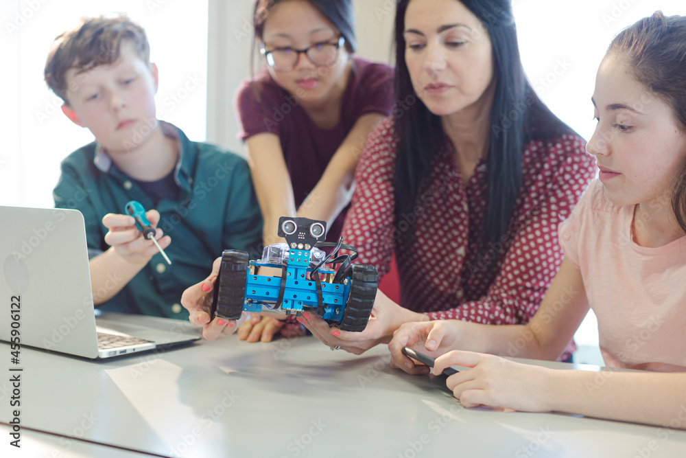 Female teacher and students playing with robot in classroom Female teacher and students playing with robot in classroom