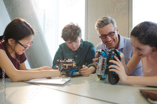 Male teacher and students playing with robot in classroom