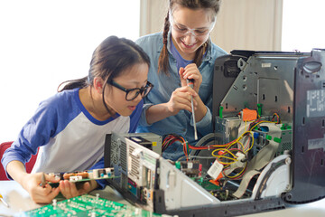 Girl students assembling computer in classroom