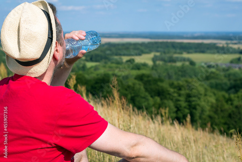 Traveler drinks water in the mountains.Hiker with backpack relaxing on top of the mountain in summer sunny day.