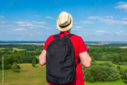 Young man admiring beautiful view of the forest landscape rear view.Young man standing alone summer day outdoors.