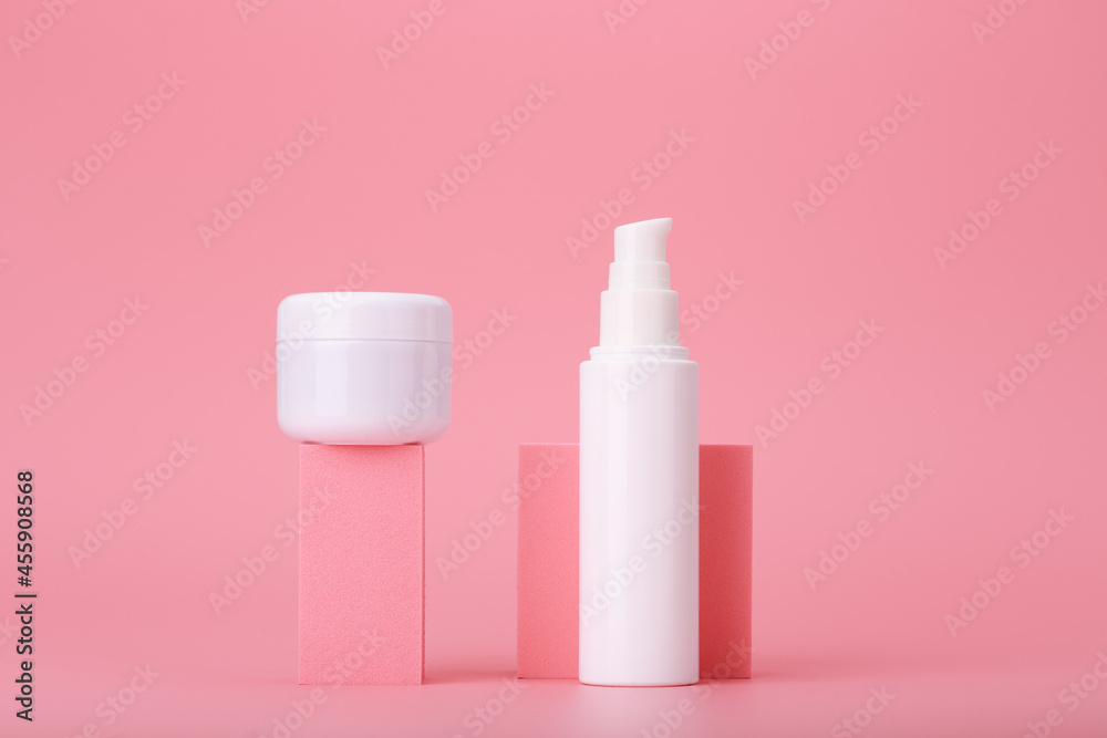 Modern trendy set of two white cosmetic jars on pink geometric shapes for product presentation against pink background. Minimal concept of skin care creams for face and under eye area or lips Modern trendy set of two white cosmetic jars on pink geometric shapes for product presentation against pink background. Minimal concept of skin care creams for face and under eye area or lips