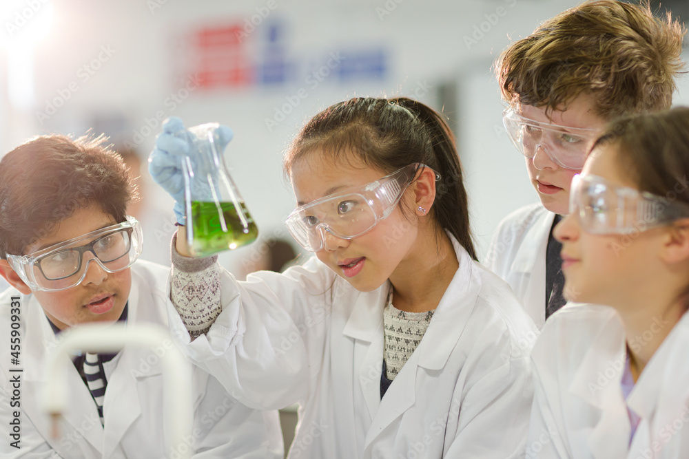 Curious students conducting scientific experiment, examining liquid in beaker in laboratory classroom Curious students conducting scientific experiment, examining liquid in beaker in laboratory classroom
