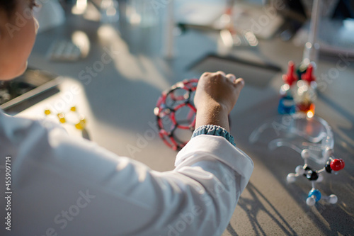 Girl student examining and touching molecular structure in classroom