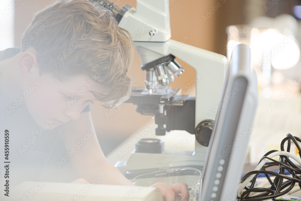 Focused boy student using microscope in classroom Focused boy student using microscope in classroom