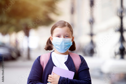 School girl with face mask in front of her school
