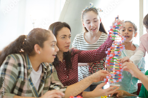 Female teacher and students examining DNA model in classroom