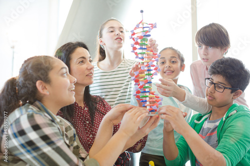 Female teacher and students examining DNA model in classroom