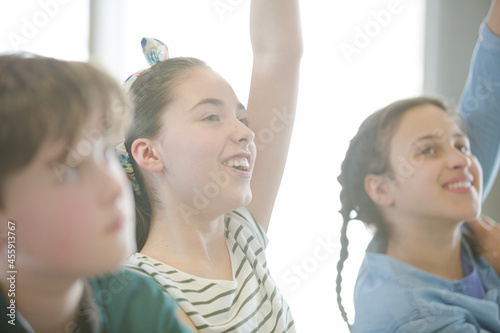 Eager  smiling students raising hands in classroom