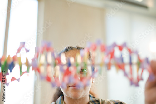 Girl student examining DNA model in classroom