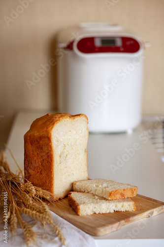 Sliced bread from a bread maker with wheat spikelets on a board with a kitchen napkin