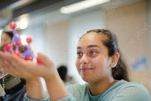 Curious girl examining molecule model in classroom