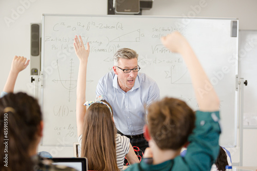 Fotografija Male teacher leading lesson at whiteboard in classroom