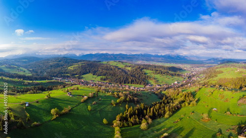 View from above on beautiful green meadows, snow-capped peaks of the Tatra Mountains in the distance. View from the air. View from the drone.