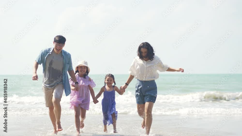 Asian family on summer vacation. Parents with two child girl kid walking on the beach with playing sea water together. Two sisters sibling having fun outdoor lifestyle activity with father and mother. Asian family on summer vacation. Parents with two child girl kid walking on the beach with playing sea water together. Two sisters sibling having fun outdoor lifestyle activity with father and mother.