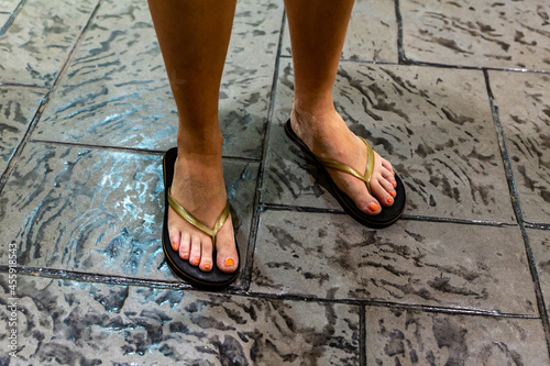 woman in flip flops against gray floor of coastal bar