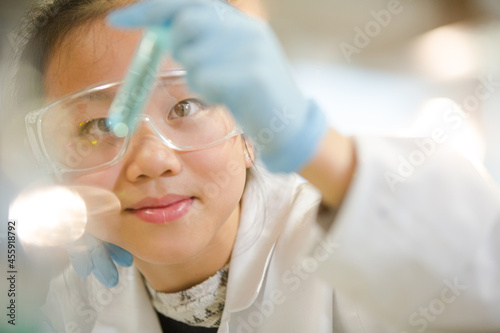Girl students conducting scientific experiment  examining liquid in test tube in laboratory classroom