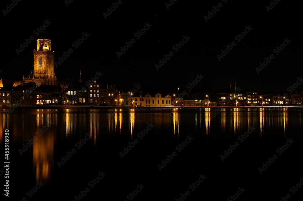 A view on  the houses and the Great Church in the City of Deventer, the Netherlands, at night with reflection in the water