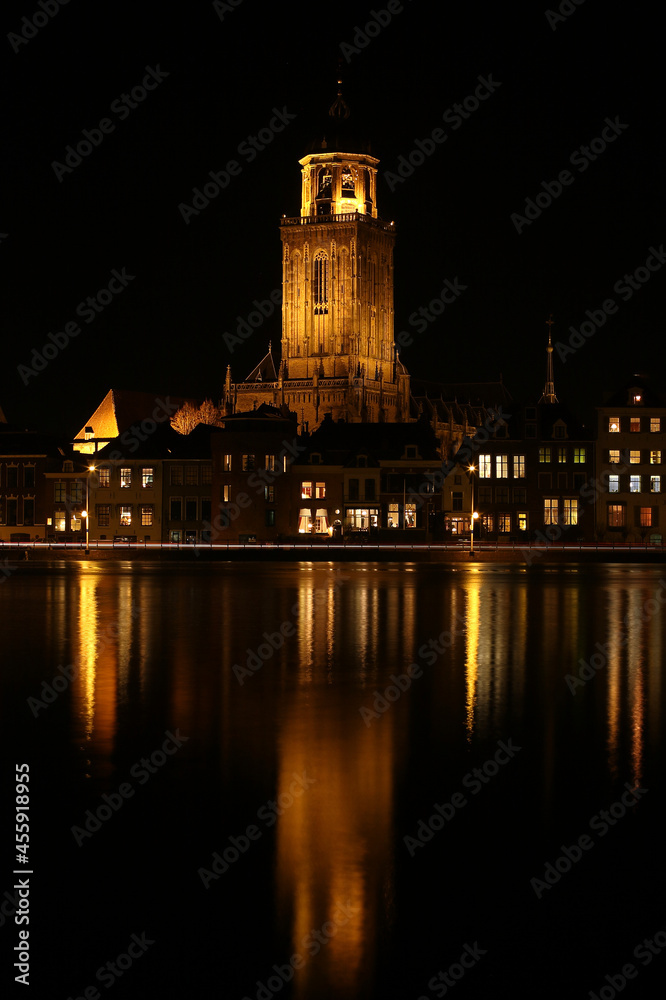 A view on  the houses and the Great Church in the City of Deventer, the Netherlands, at night with reflection in the water