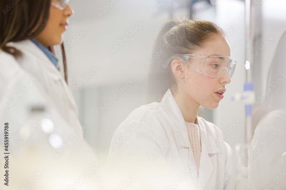 Girl students conducting science experiment in classroom laboratory Girl students conducting science experiment in classroom laboratory