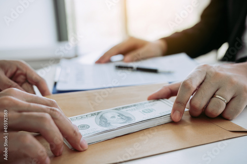 Partner has made a fraud in the contract of sale and being handed a cash and pen to the businessman signing the contract corruption bribery concept.
