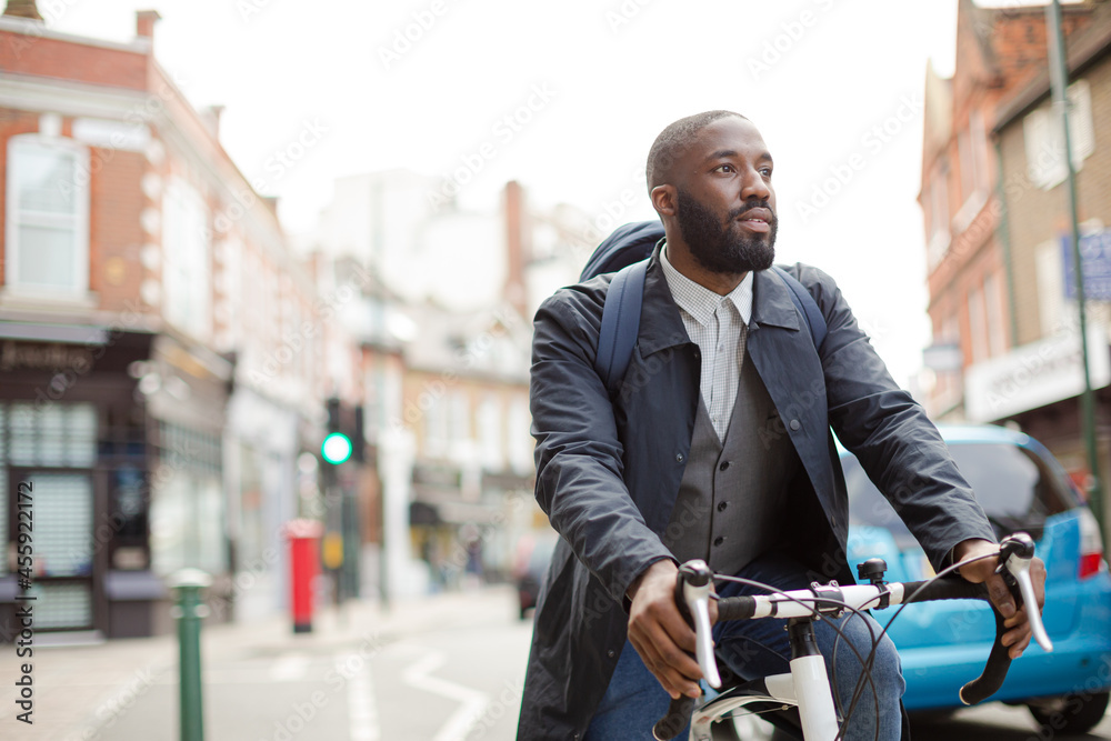 African businessman commuting, riding bicycle on urban street African businessman commuting, riding bicycle on urban street