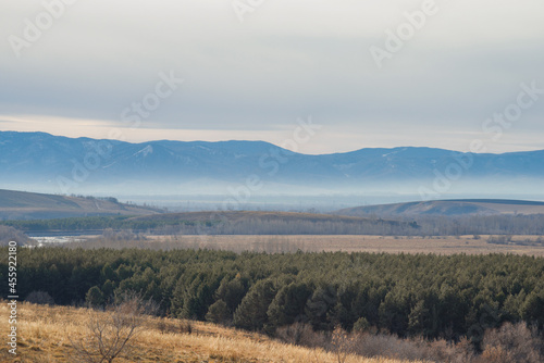 Foggy autumn landscape of mountains with valleys and river.