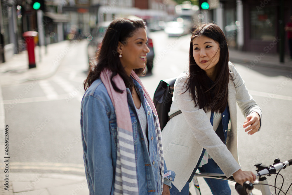 Smiling women friends talking on urban street