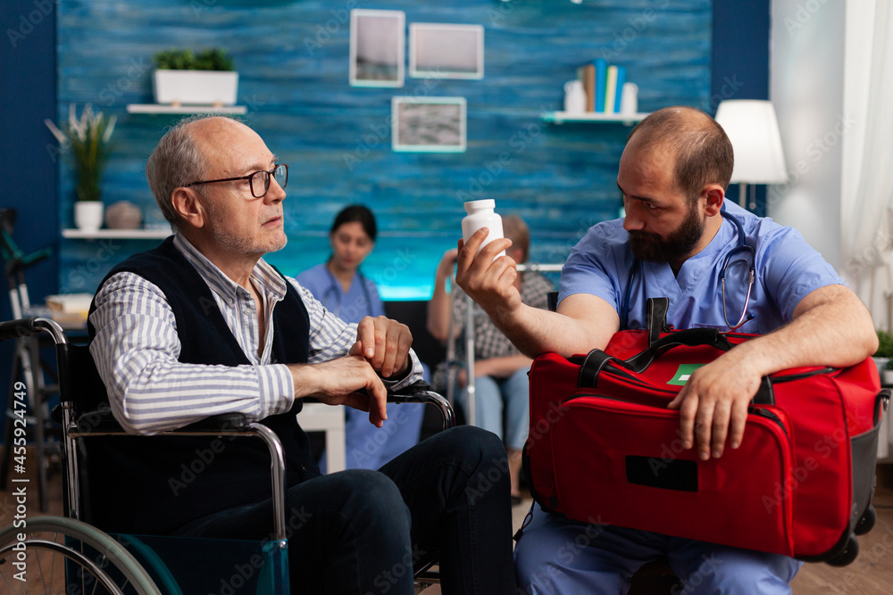 Support nurse worker explaining pills treatment to senior man holding emergency medicine kit bag in hands during therapy. Social services nursing elderly retired male. Healthcare assistance Support nurse worker explaining pills treatment to senior man holding emergency medicine kit bag in hands during therapy. Social services nursing elderly retired male. Healthcare assistance