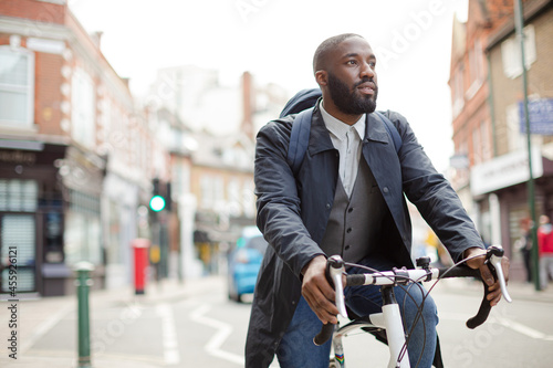African businessman commuting, riding bicycle on urban street