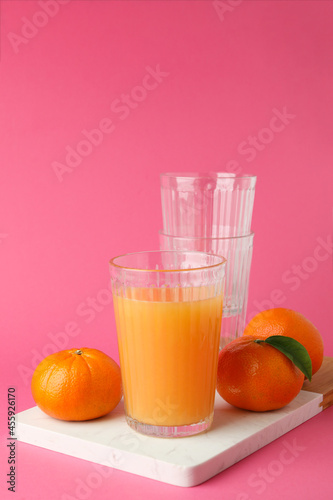 Board with mandarin juice and ingredients on pink background