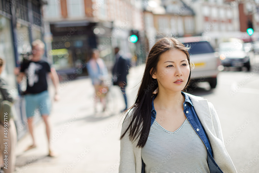 Serious, pensive young woman walking on urban street