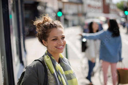 Portrait smiling young woman on sunny urban street