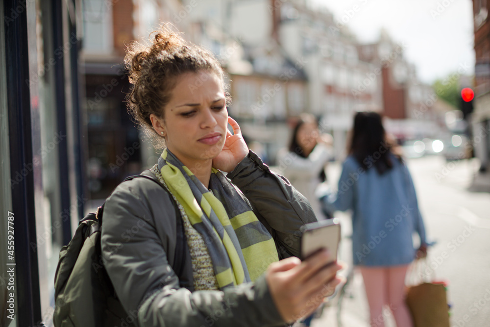 Young woman texting on sunny urban street