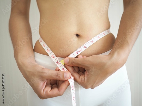 Overweight woman measures her waist circumference. concepts about exercise, fitness or diet. closeup photo, blurred.
