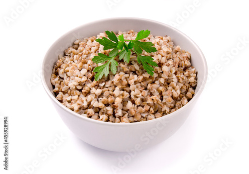 Boiled buckwheat in a plate with parsley leaf and butter on a white