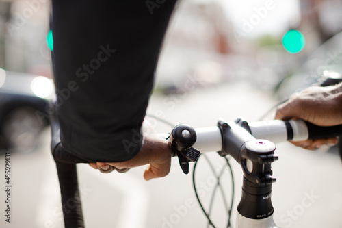 Hands on man on bicycle handlebars, commuting on sunny urban street