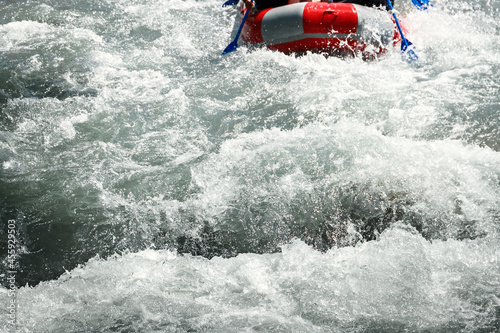 Rapid rapids of a mountain river with rafting tourists in an inflatable raft with copy space