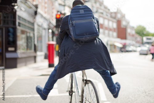 Playful young businessman commuting, riding bicycle on sunny urban street