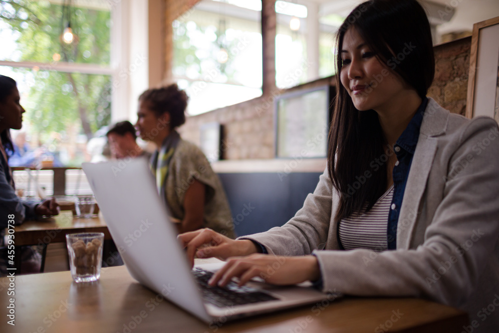 Young woman using laptop and drinking coffee in cafe Young woman using laptop and drinking coffee in cafe