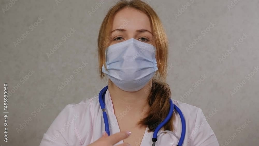 Portrait of a woman doctor in a hospital in a medical mask, she puts a stethoscope around her neck. Portrait of a woman doctor in a hospital in a medical mask, she puts a stethoscope around her neck.